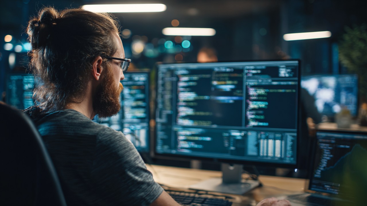 Modern çalışma alanında çift monitörlü kod optimizasyonu yapan web geliştirici, performans grafikleri ve hız artırma stratejileriyle.